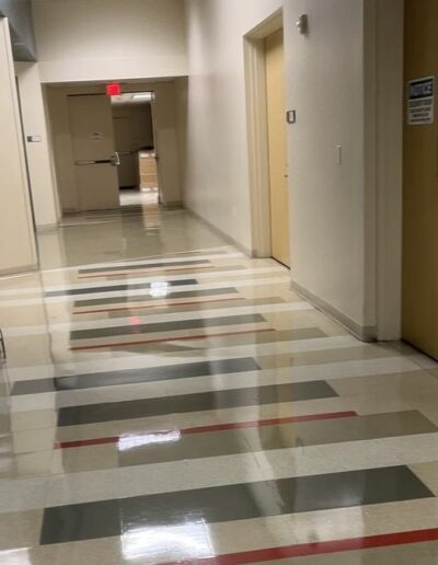 Cropped view of glossy terrazzo tile hallway floor with wooden doors in an office corridor