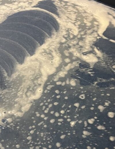 Close-up of blue tile floor covered in foam during scrubbing machine cleaning