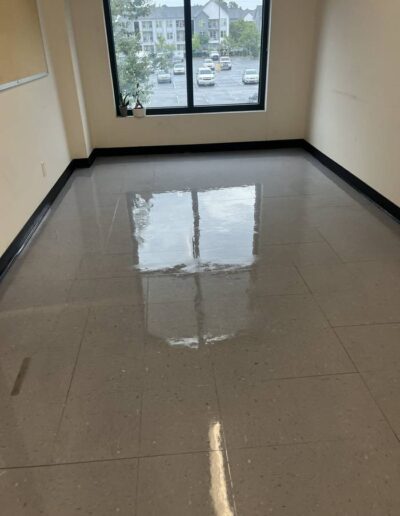 Freshly waxed tan tile floor reflecting light in an empty office room with a window