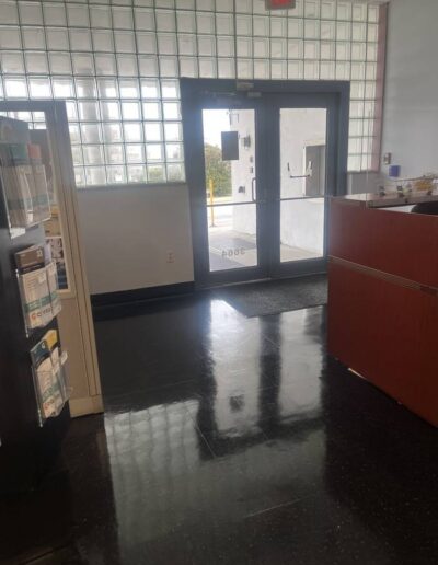 Shiny black floor near glass entrance doors and reception desk after floor waxing