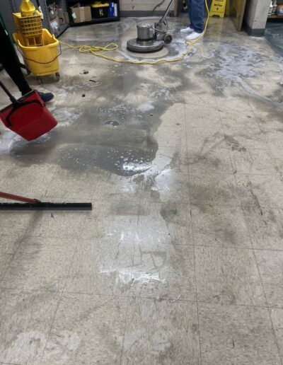 Floor buffing machine and mop bucket in use during commercial tile floor cleaning
