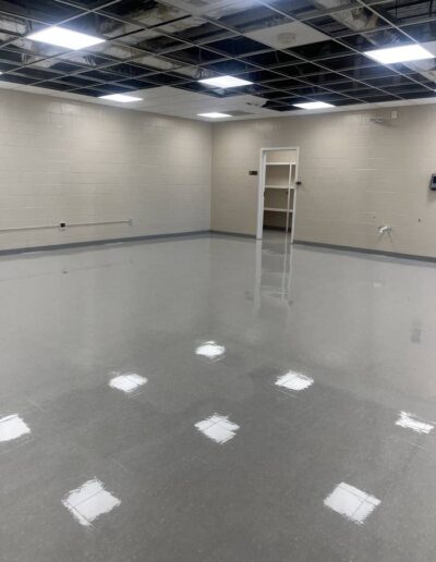 Polished concrete floor in an empty commercial room with exposed ceiling grid