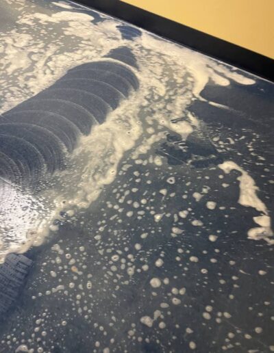 Blue tile floor covered in foam being scrubbed clean with a floor buffing machine